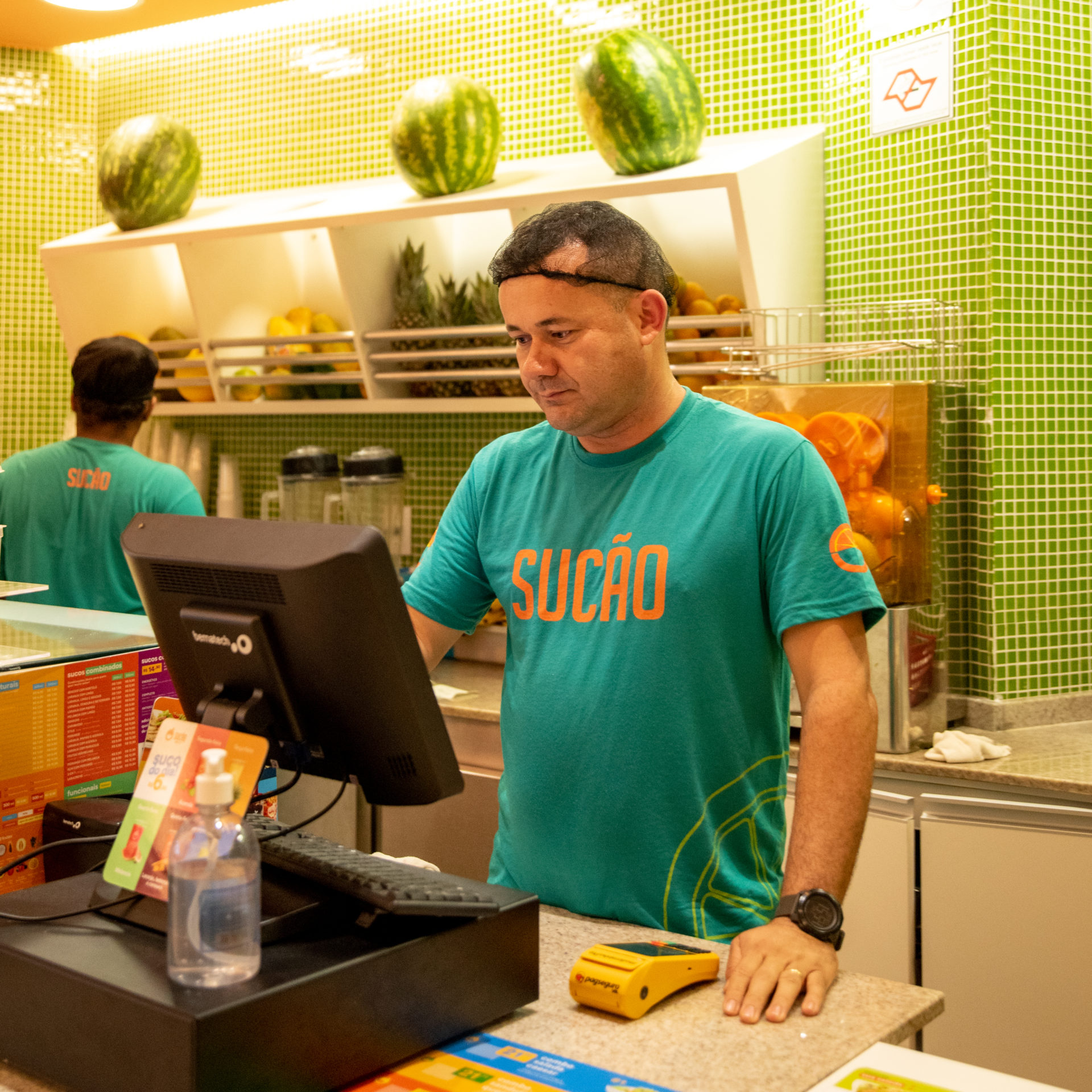 Homem de camisa verde trabalhando no caixa de um restaurante de comida saudável