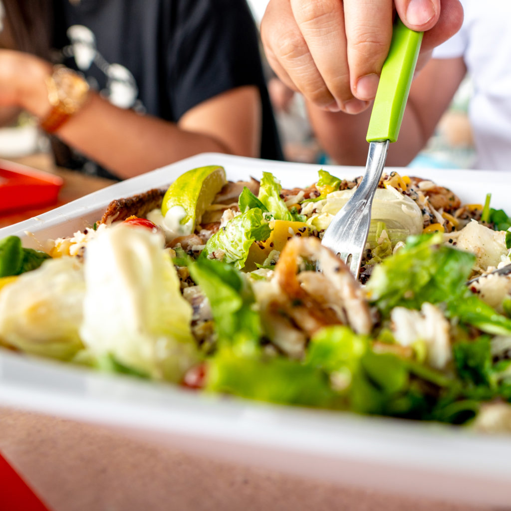 Pessoa-utilizando-garfo-verde-para-pegar-uma-salada-em-um-bowl-branco